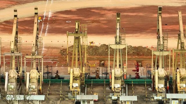Elevated drone shot of synchronized pumpjacks in an oil field, symbolizing large-scale petroleum extraction, energy security, and the balance between economic growth and sustainability.
