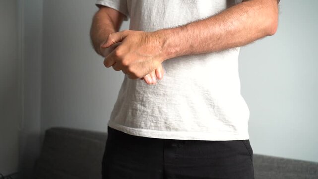 Young man massaging his painful wrist due to carpal tunnel syndrome, arthritis or injury