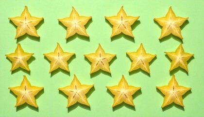 Obraz premium Bright yellow star fruit slices arranged neatly on a vibrant green background, showcasing their unique star shape.