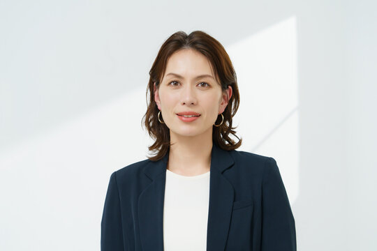 白背景の紺のジャケットを着るミドルエイジの女性
