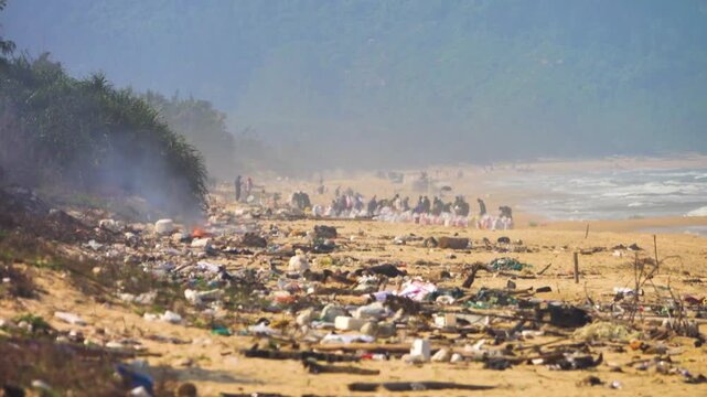 Oil spill clean-up. An environmental disaster. Volunteers collect oil stains and clumps, soiled floatsam debris on the coast of the South China Sea after an oil spill in hot weather