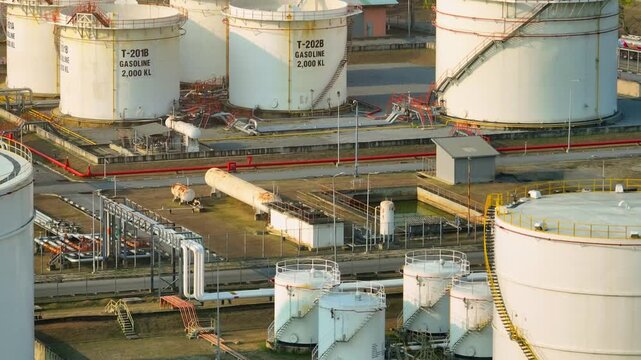 Drone video capturing oil storage tanks under sunlight, emphasizing the importance of petroleum infrastructure in maintaining steady fuel distribution and economic stability.
