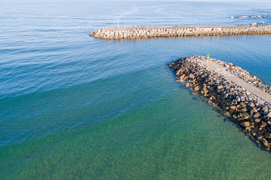 Calm light green sea meeting rugged rock and concrete coastal barriers