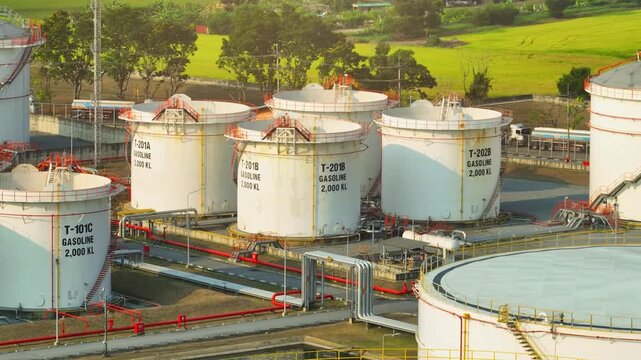 High-angle drone shot of oil storage facility with circular tanks, illustrating critical petroleum reserves that stabilize energy markets during supply disruptions and geopolitical tensions.
