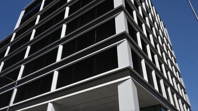 Modern business building facade with white pillars and black windows