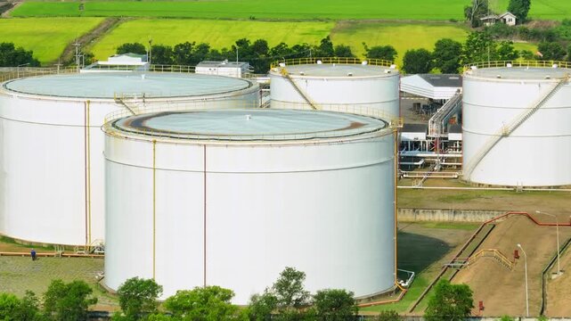 Aerial drone view of oil storage tanks with pipelines and access stairs, reflecting global fuel reserves, energy security concerns, and the strategic role of petroleum in today&rsquo;s volatile markets.
