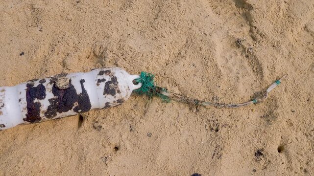 Oil pollution of sea, coast. Floating objects (flotsam, trawl float) are covered with fuel oil and bring toxin to other parts of sea, secondary pollution. Sandy beach attacked by fuel. South China Sea