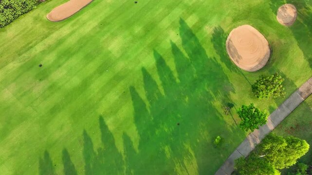 Top view drone shot of a green golf course with structured fairways and natural elements, representing eco-friendly leisure activities and sustainable land management practices.
