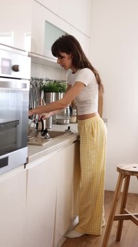 A young woman in the kitchen is preparing coffee in the morning.
