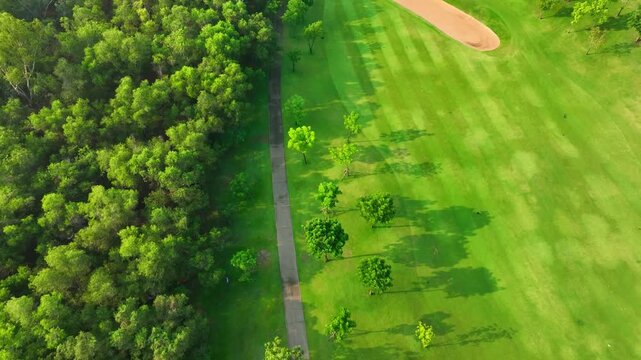 An aerial view capturing a scenic golf course with geometric grass patterns and winding paths, emphasizing eco-conscious design and recreational spaces aligned with contemporary sustainability goals.

