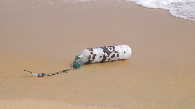 Oil pollution of sea, coast. Floating objects (flotsam, trawl float) are covered with fuel oil and bring toxin to other parts of sea, secondary pollution. Sandy beach attacked by fuel. South China Sea