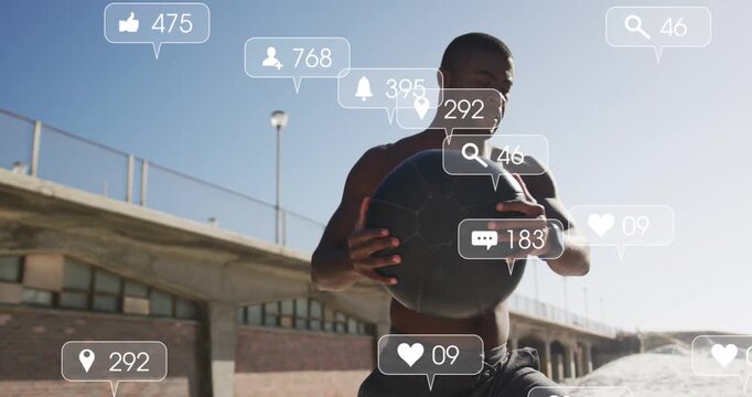 Vertical video: Male athlete cradling med ball on pier for fitness, causing social icons over torso