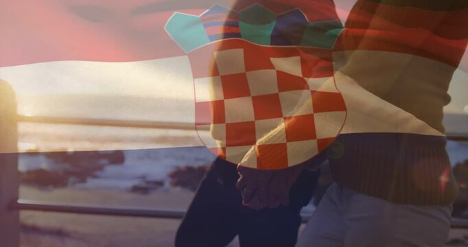 Vertical video: Couple walking sea sunset hand reaching clasping under rippling flag crest tourism