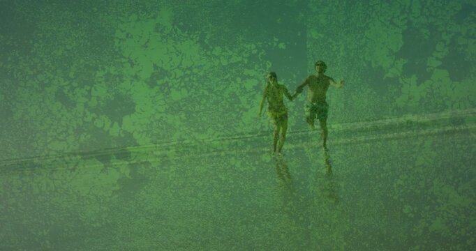 Vertical video: Starting swimsuit couple walking then running toward lens on wet sand for fun