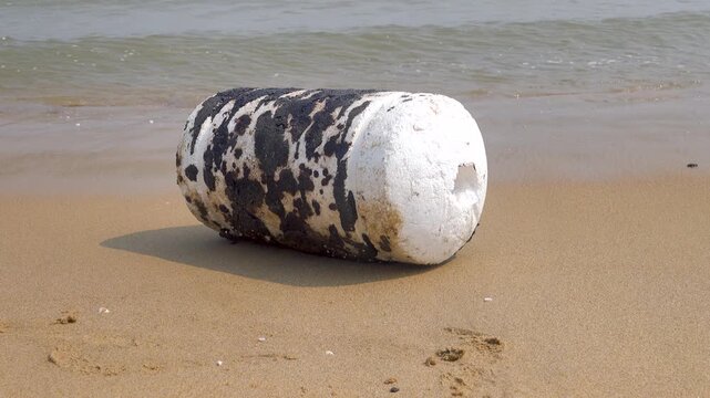 Oil pollution of sea, coast. Floating objects (flotsam, trawl float) are covered with fuel oil and bring toxin to other parts of sea, secondary pollution. Sandy beach attacked by fuel. South China Sea