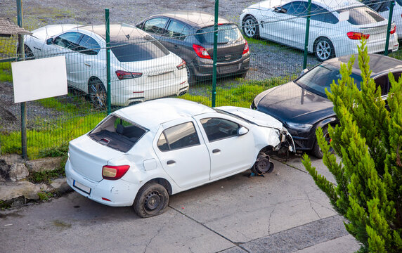 Car accident takes place in a parking lot with damaged vehicles and surrounding cars during the day
