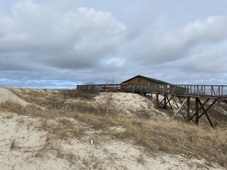 Obraz premium Wooden viewing platform and boardwalk on the sand dunes of the Curonian Spit National Park under a cloudy sky