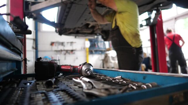 Mechanic performing car repair in a busy auto service garage, showcasing a sequence of actions with tools and equipment, highlighting the intricate process of vehicle maintenance and teamwork