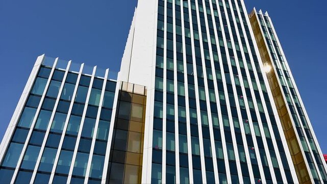 Modern glass building exterior with white pillars and blue sky