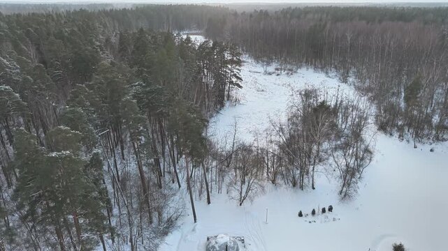 Aerial panorama of igloo-shaped glamping cabins in snowy winter forest.
Drone view of unique stays surrounded by nature.