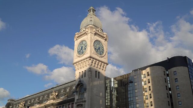 Clock tower of Gare de Lyon train station in Paris, France. Sunny afternoon, blue sky with white clouds.