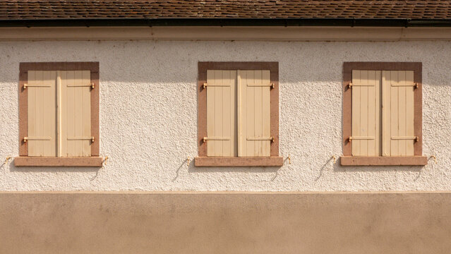 Three Closed Windows with Shutters on a Stucco Wall