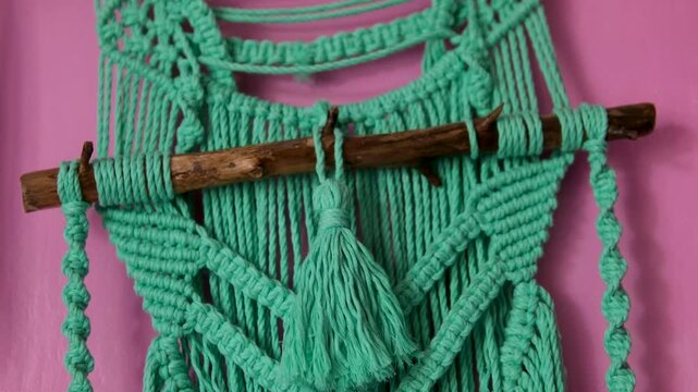 Green macrame wall-hanging Green potted plant in white pot sits near wooden room divider with macrame wall hanging