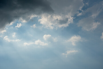 Fototapeta premium Sun Rays Breaking Through Dark and Light Clouds in Blue Sky