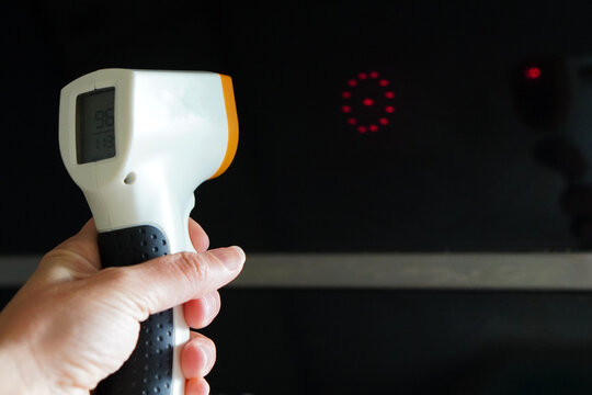 Hand using an infrared thermometer to measure the temperature of a black surface