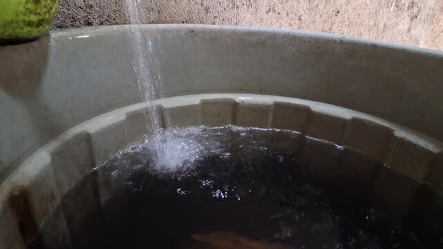 Water pouring into tub close up view plastic bucket filling splash liquid storage resource management household sustainability concept highlighting water scarcity and essential basic needs for hygiene