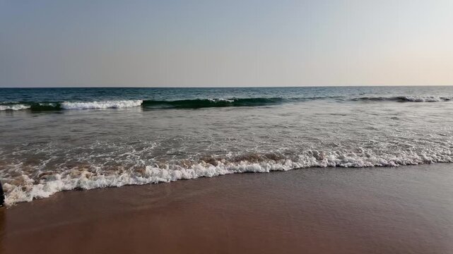 Gentle Ocean Waves on Sandy Beach Shoreline Under Clear Sky