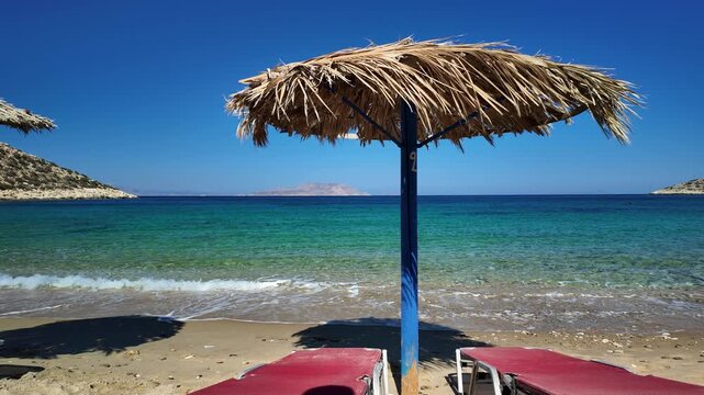 Sun beds and a sun umbrellas at the stunning sandy and turquoise beach of Agia Theodoti in Ios Greece