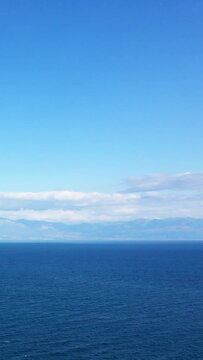 Tranquil seascape with deep blue water and distant mountains under a clear sky, captured near Koroni, Greece.