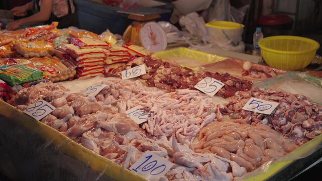 Raw meat displayed at market stall with variety of cuts and poultry, fresh food ingredients at street vendor, traditional wet market scene, food supply and local commerce concept