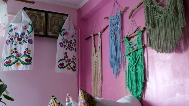 icons with Ukrainian embroidered towel on the wall in a village hut Handmade macrame wall decor on pink rural house wall with traditional woven patterns creating cozy boho atmosphere and authentic 