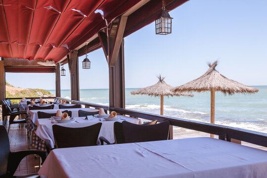A covered outdoor beach restaurant, chiringuito, overlooking the ocean on a bright sunny day, Spain