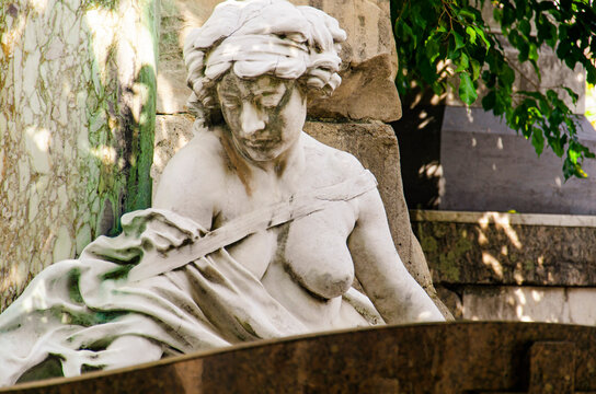 Female sculpture in white marble.The figure has part of her breasts exposed, a serene expression, and a downward gaze. Artist unknown, S&atilde;o Jo&atilde;o Batista Cemetery, RJ, Brazil.