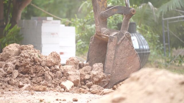 Earthmoving Excavator at Work: The powerful scoop of an excavator tears into the earth, creating a sense of construction and ground work.