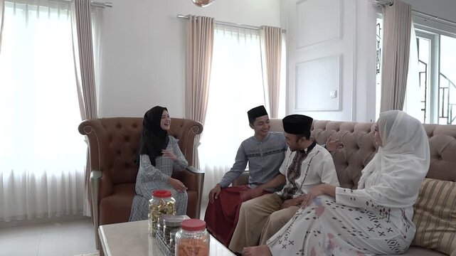 Family greeting elders during festive home visit, young relatives offer hugs and handshakes, living room with sofa and sunlit
