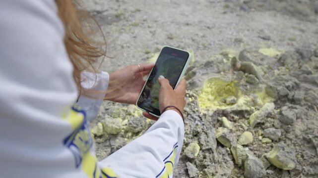 Woman takes photos of the sulfur on the volcano of Mendeleev on Kunashir island. Russia