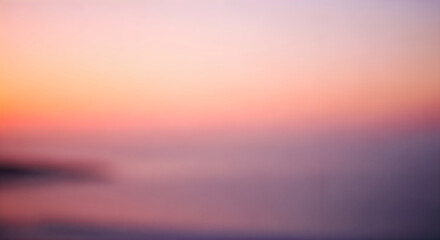 Fototapeta premium Blurry sunset over water with a colorful sky and silhouette of land