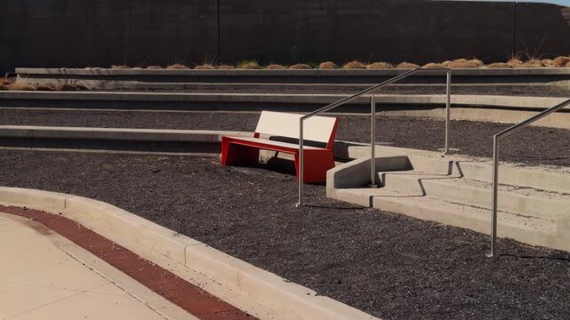 Slow steady left to right glide following bench and concrete steps in modern outdoor plaza.