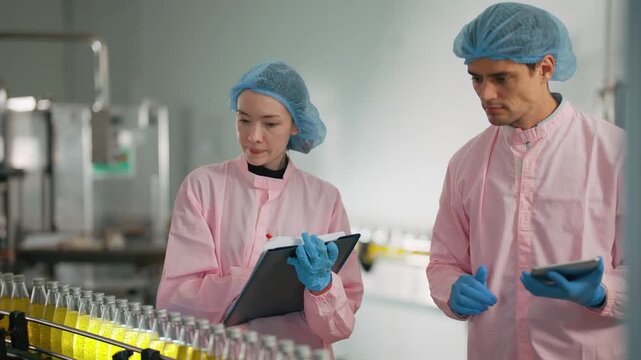 Bottling Line Inspection: Two lab-coated professionals meticulously inspect a production line, their focused gaze and careful documentation highlighting their dedication to precision.