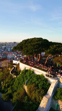 Aerial rise of people watching sunset at Senhora do Monte viewpoint in Graca, Lisbon Portugal, vertical video