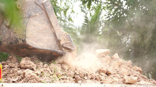 Earth Mover in Action: A close-up shot of an earth mover efficiently moving earth in a cloud of dust, showcasing the power of construction equipment.