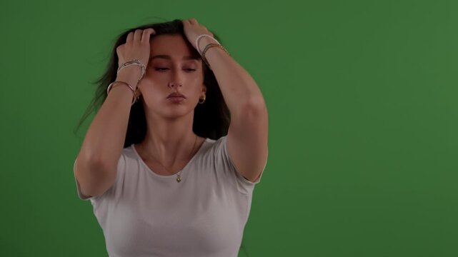 Self-care and beauty - a young woman with long brunette hair tosses her hair in slow motion against a green screen Shot in a studio setting this clip is commercial projects related to cosmetics fashio