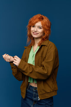 Young woman with vibrant red hair showcases spring fashion on a striking blue backdrop
