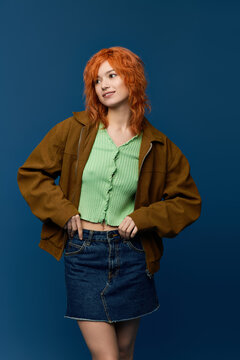 Spring fashion: a young woman with red hair in a stylish outfit on blue
