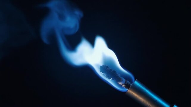 Burning matchstick with flame and smoke on a black background