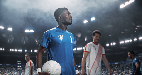 Black Male Soccer Captain in Blue Carries the Match Game Ball Onto the Field Before Kickoff, Leading Players Into a Professional International Football Tournament at a World Stadium Euro Cup © Gorodenkoff
